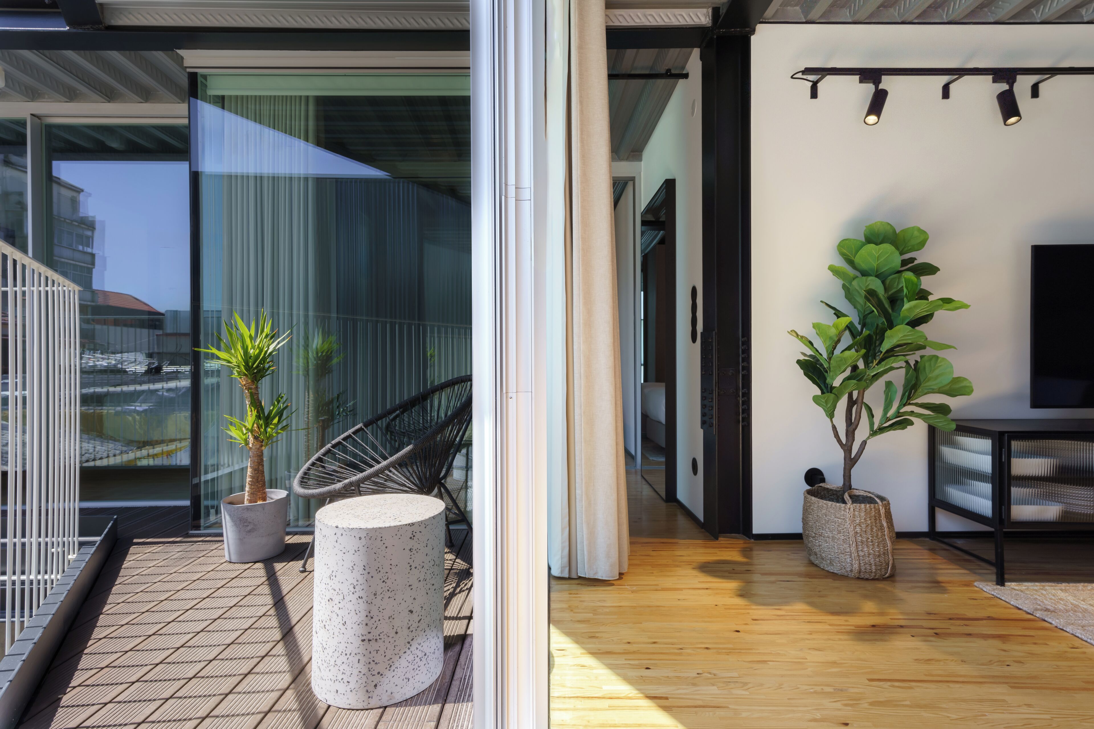 Ein modernes Interieur mit Balkon, einer Sitzecke und einer großen Pflanze.