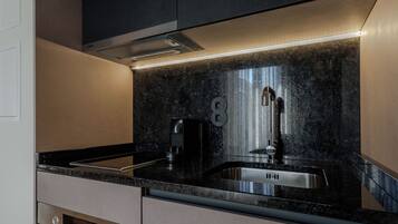 Una cocina moderna con encimera negra, electrodomésticos de acero inoxidable y horno empotrado.