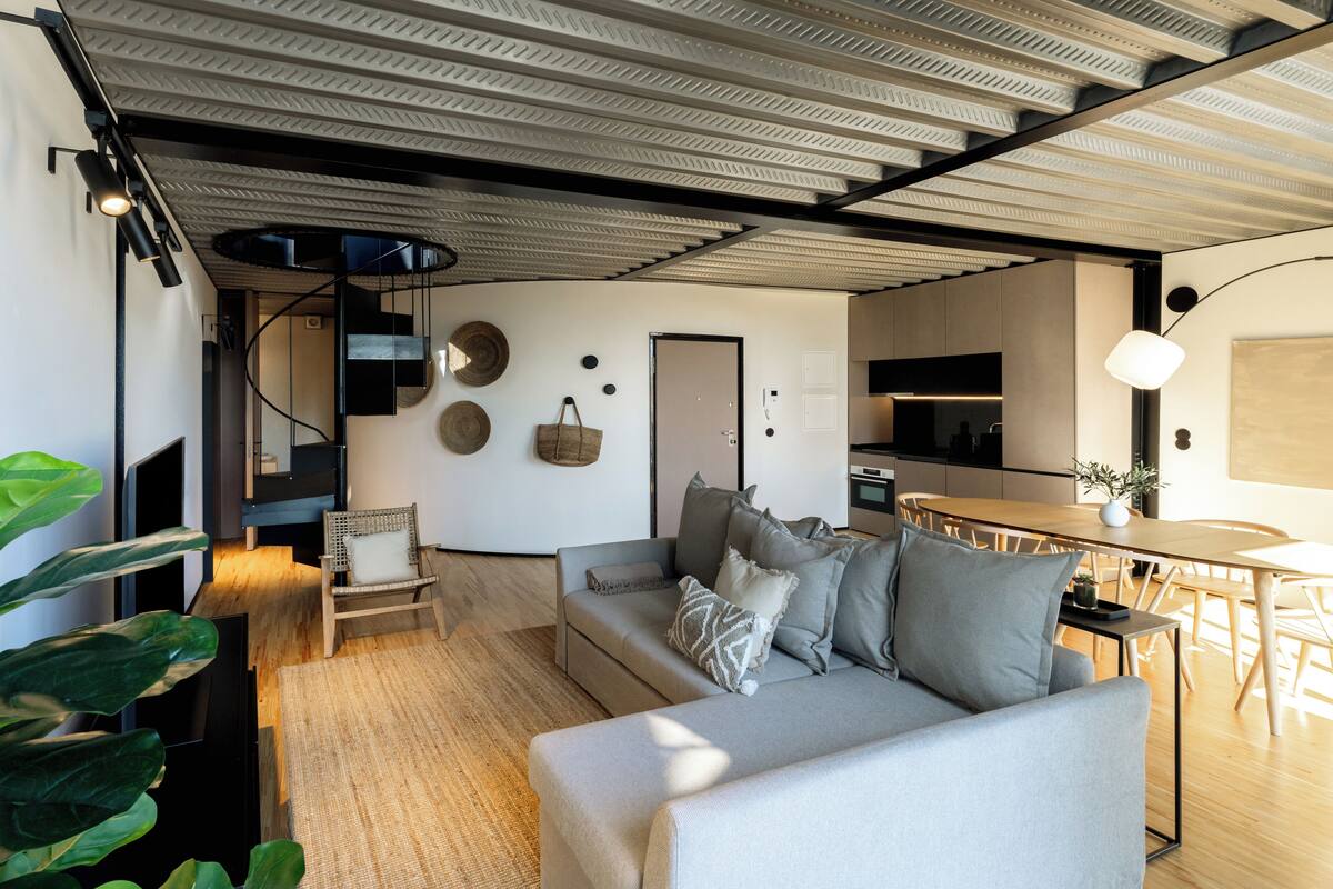 Un salon moderne avec un canapé, une table à manger et une cuisine en arrière-plan.