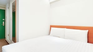 A hotel room with a bed, a wooden headboard, and a green door. - Comfort Inn Himeji Yumesakibashi (Himeji)