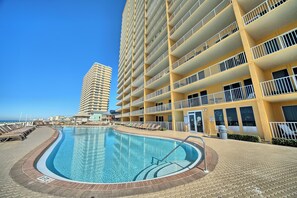 A hotel with a swimming pool, multiple balconies, and a view of the ocean. - Treasure Island 1512 (Panama City Beach)