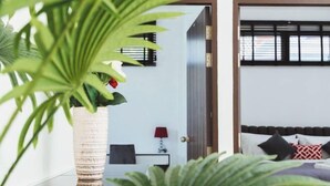 Une chambre à coucher avec un lit, une table de chevet, une lampe et une plante en pot.