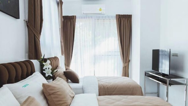 A hotel room with a bed, a TV, and curtains. - Baan Nern Khao Resort Pattaya (Pattaya)