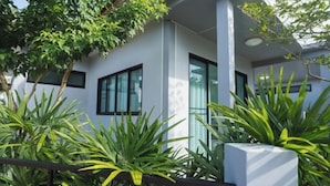 Un bâtiment moderne doté de grandes fenêtres, d’une façade blanche et entouré de verdure.