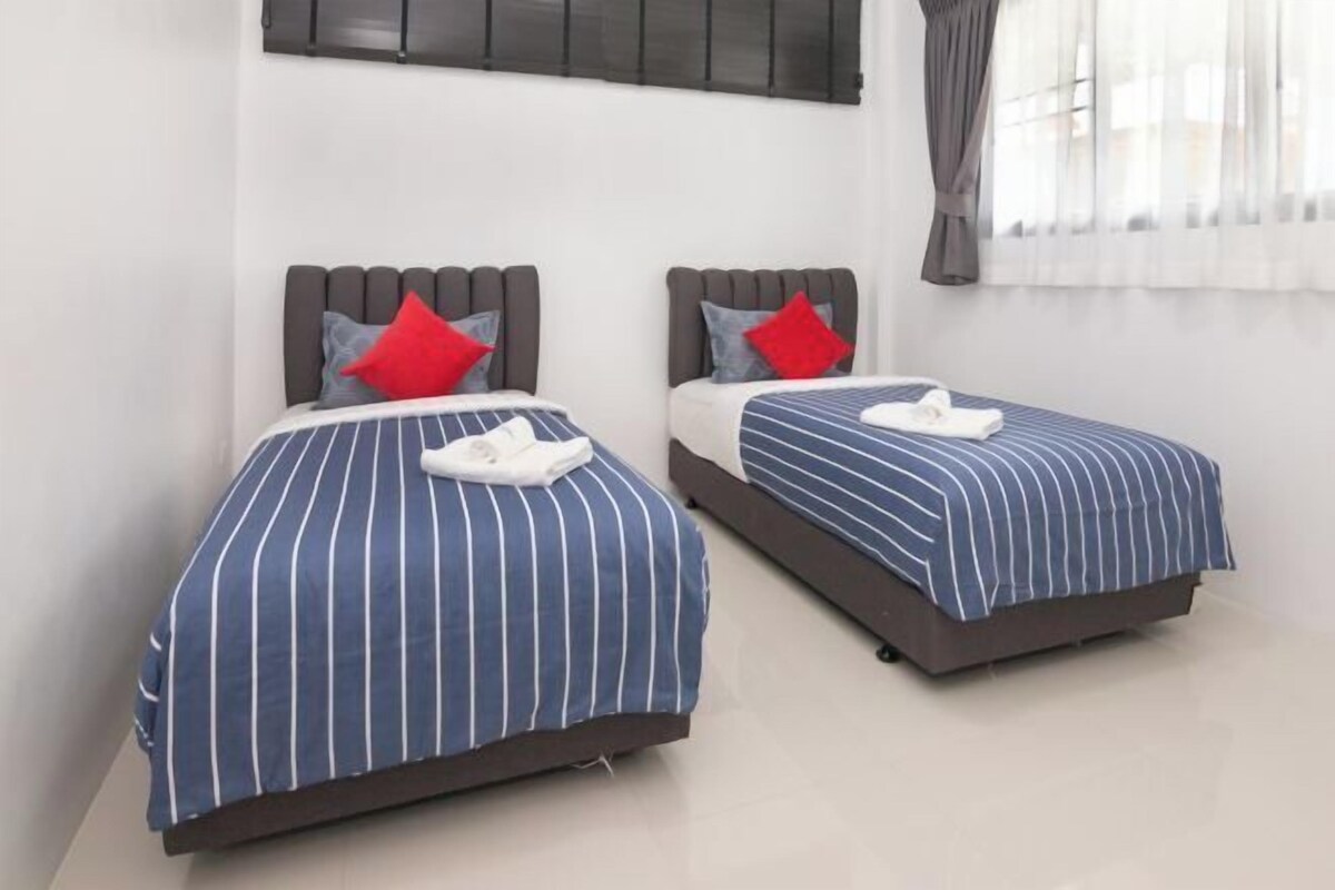 Dos camas con ropa de cama a rayas, almohadas y una toalla blanca.