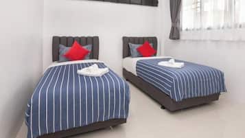 Two beds with striped bedding, pillows, and a white towel.