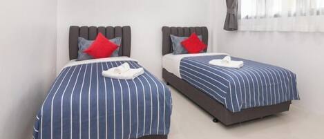 Two beds with striped bedding, pillows, and a white towel.