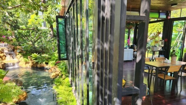 Un restaurant offrant une vue sur une petite cascade et une végétation luxuriante.