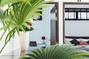 Et soveværelse med seng, et natbord, en lampe og en potteplante.