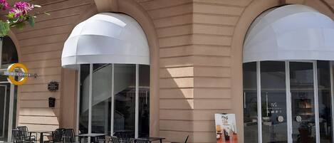 A building with large arched windows and a cafe area with outdoor seating.