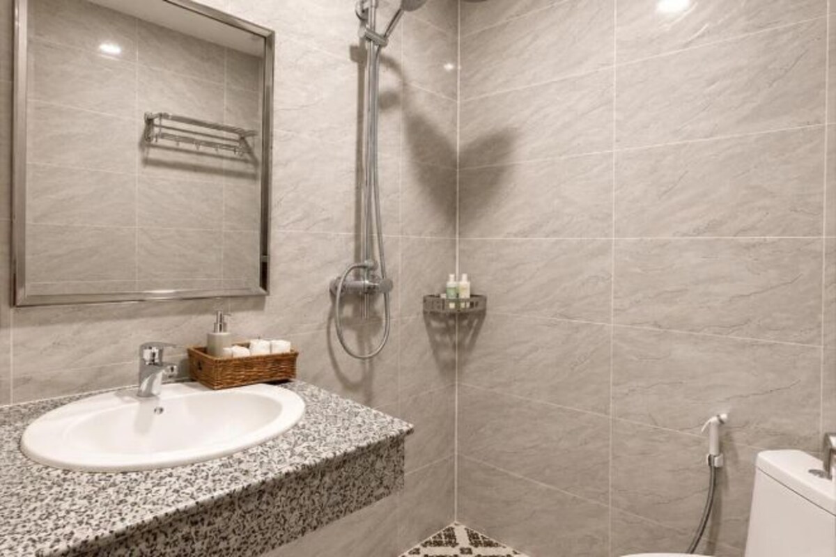 A bathroom with a sink, mirror, shower, and toilet.