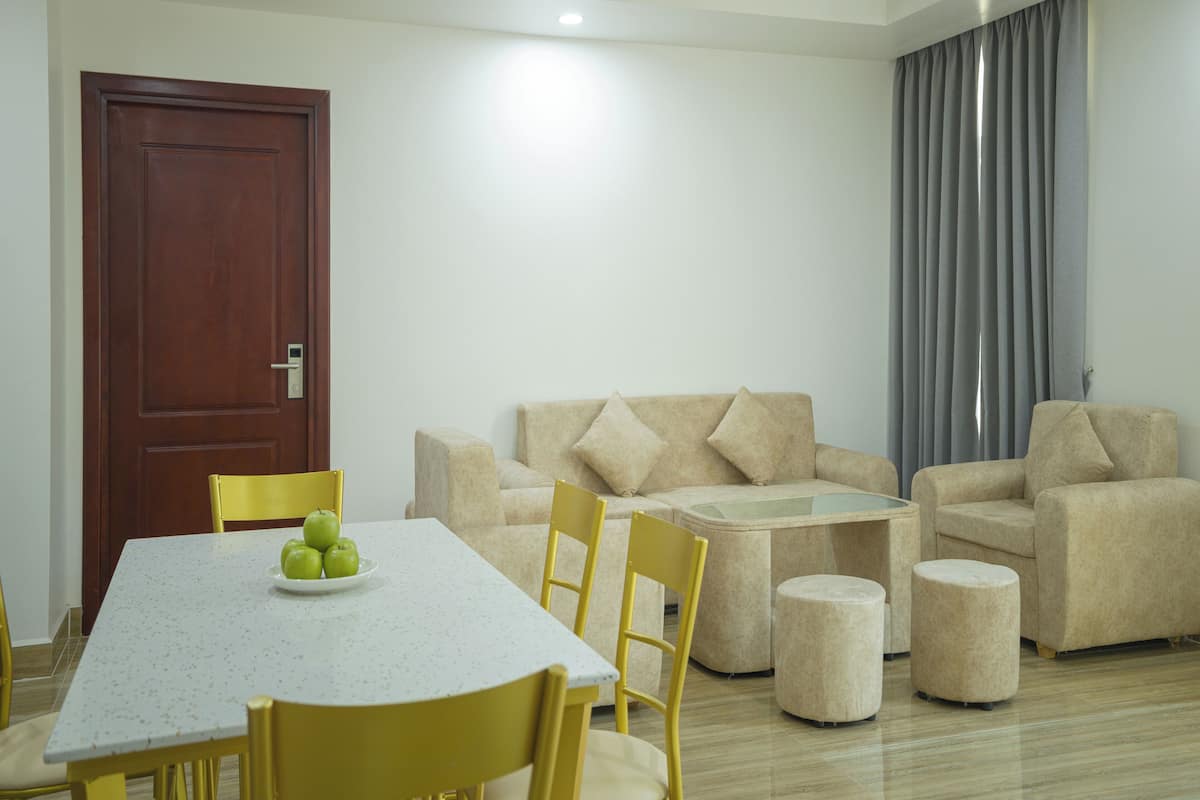 Een moderne woonkamer met een eettafel, gele stoelen, beige banken en poefs.