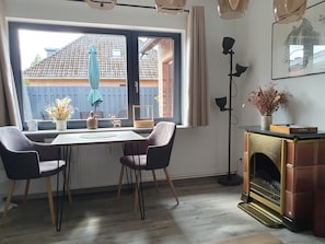 Enjoy meals with a view of the surrounding brick building and blue fence from this cozy dining area, featuring a wooden table and chairs.