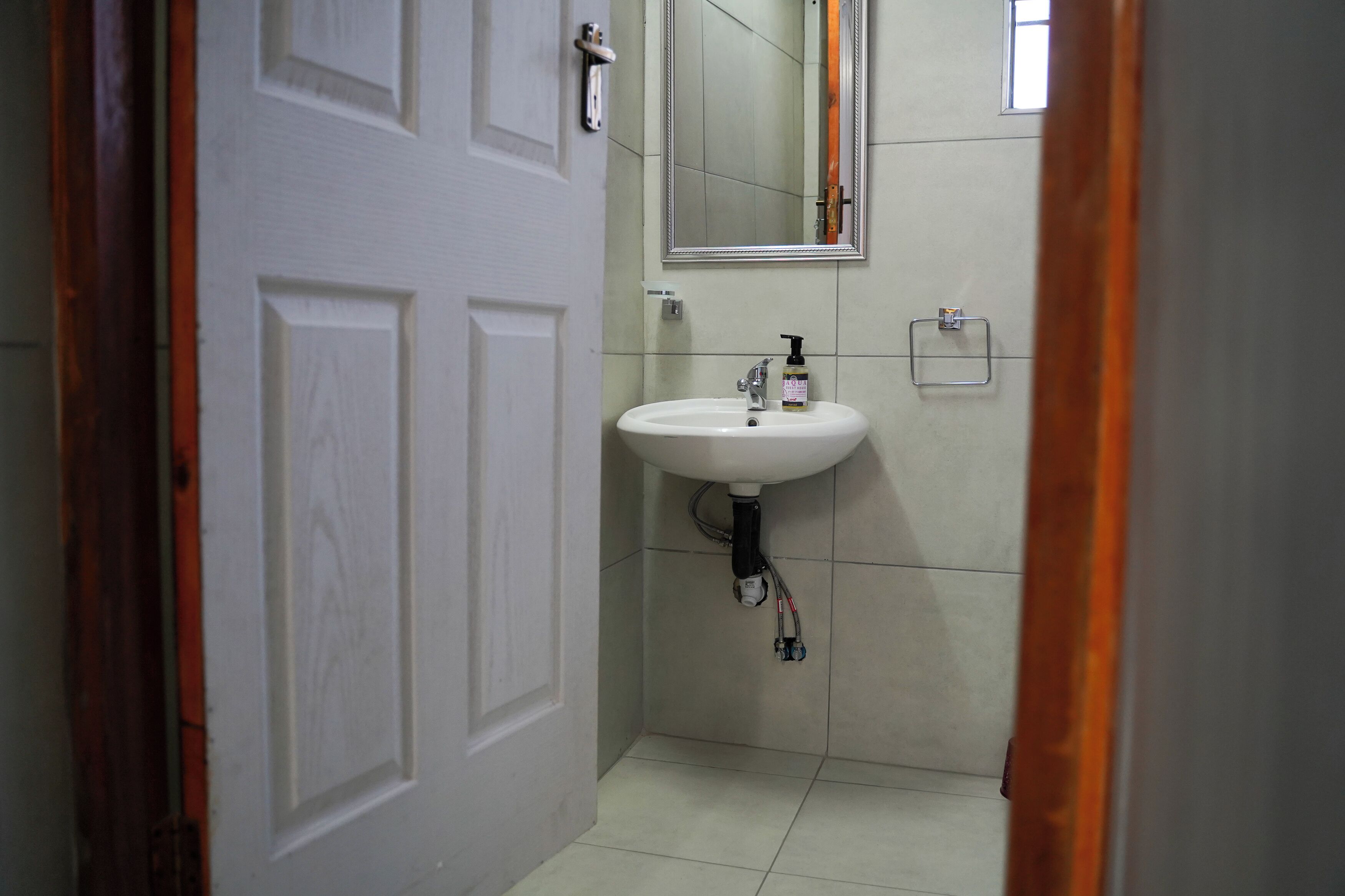 Un baño con un lavamanos blanco, un espejo y una puerta.