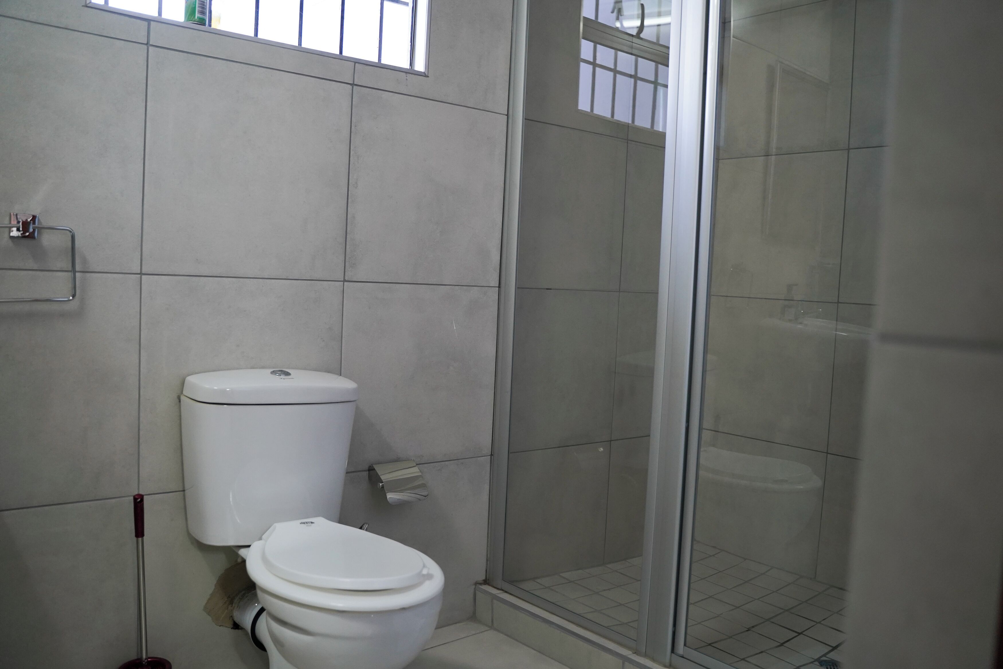 Une salle de bain avec des toilettes, une douche dotée d’une porte en verre et une fenêtre.