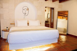 A neatly made bed in a hotel room with a large mirror and a wooden headboard. - Hanna Hotel Boutique  (Valle de Bravo)