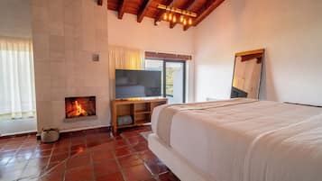 A bedroom with a fireplace, a TV, and a large bed.