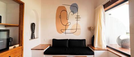 Una sala moderna con un sofá negro, una mesa de centro de madera y un mural en la pared.