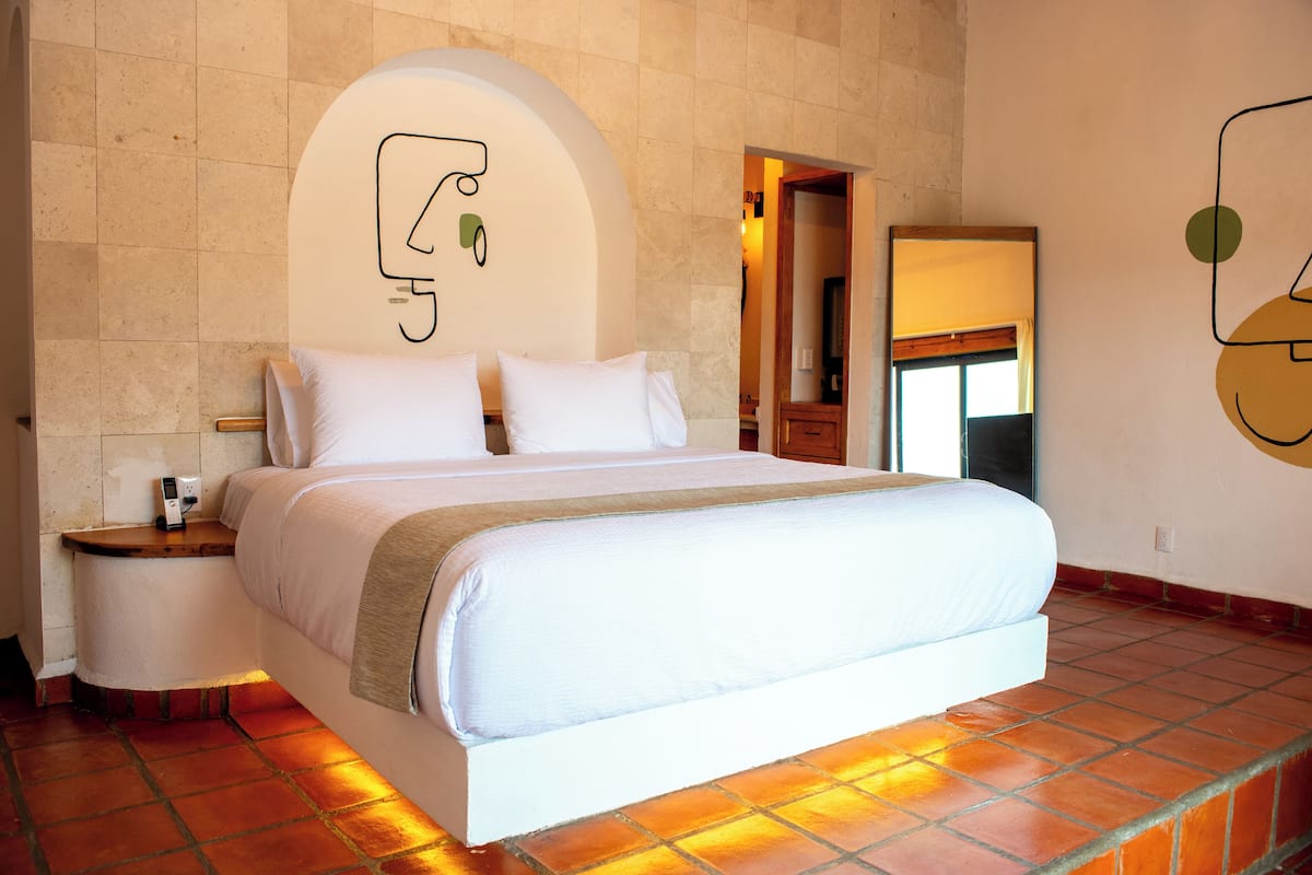 Un dormitorio con cama, mesita de noche y una obra de arte colgada en la pared.