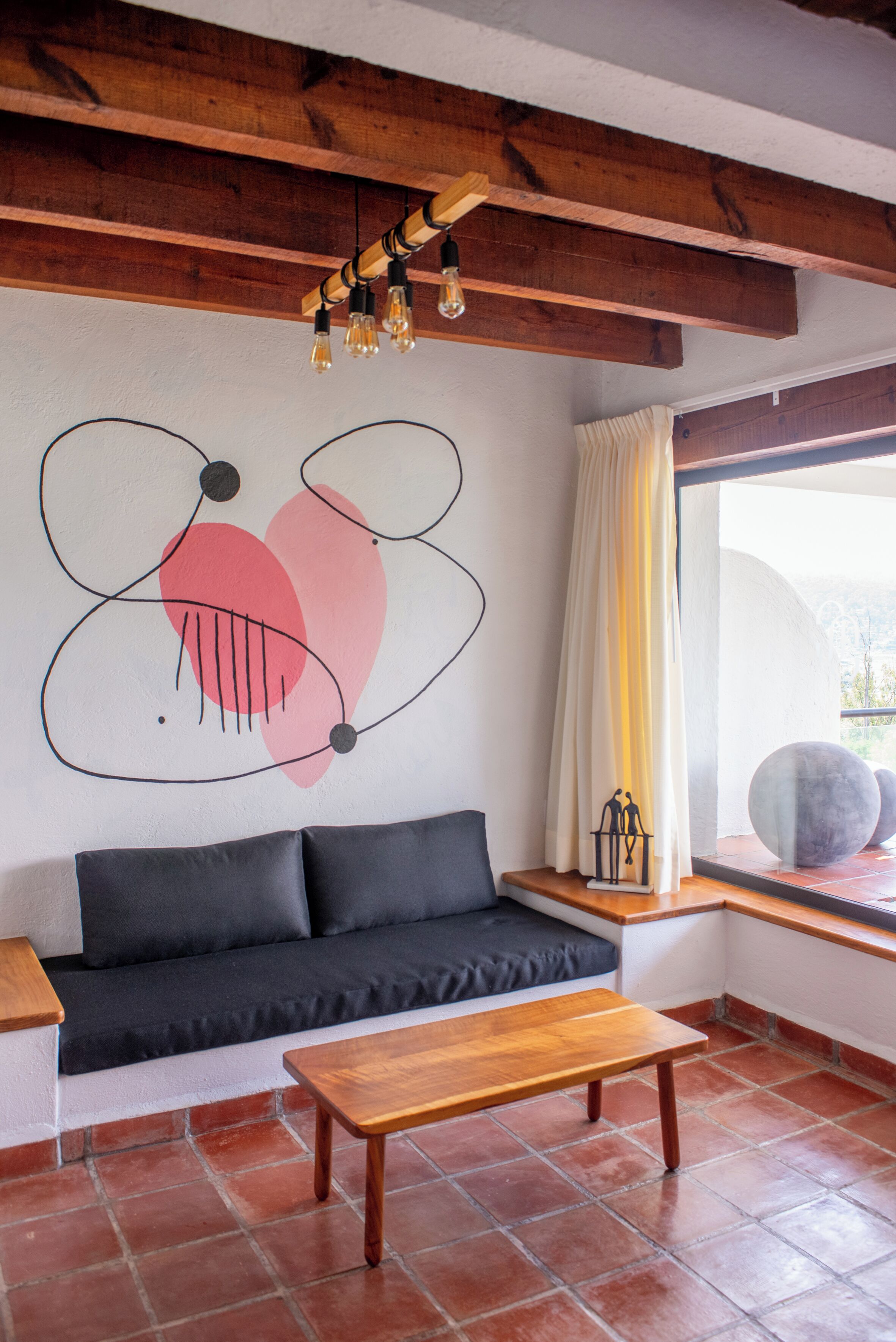 A modern living room with a wooden ceiling, a black sofa, a wooden coffee table, and a large abstract wall art piece.