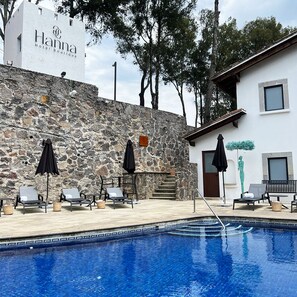 A hotel named Hanna Hotel Boutique with a stone wall, outdoor seating with umbrellas, and a swimming pool. - Hanna Hotel Boutique  (Valle de Bravo)
