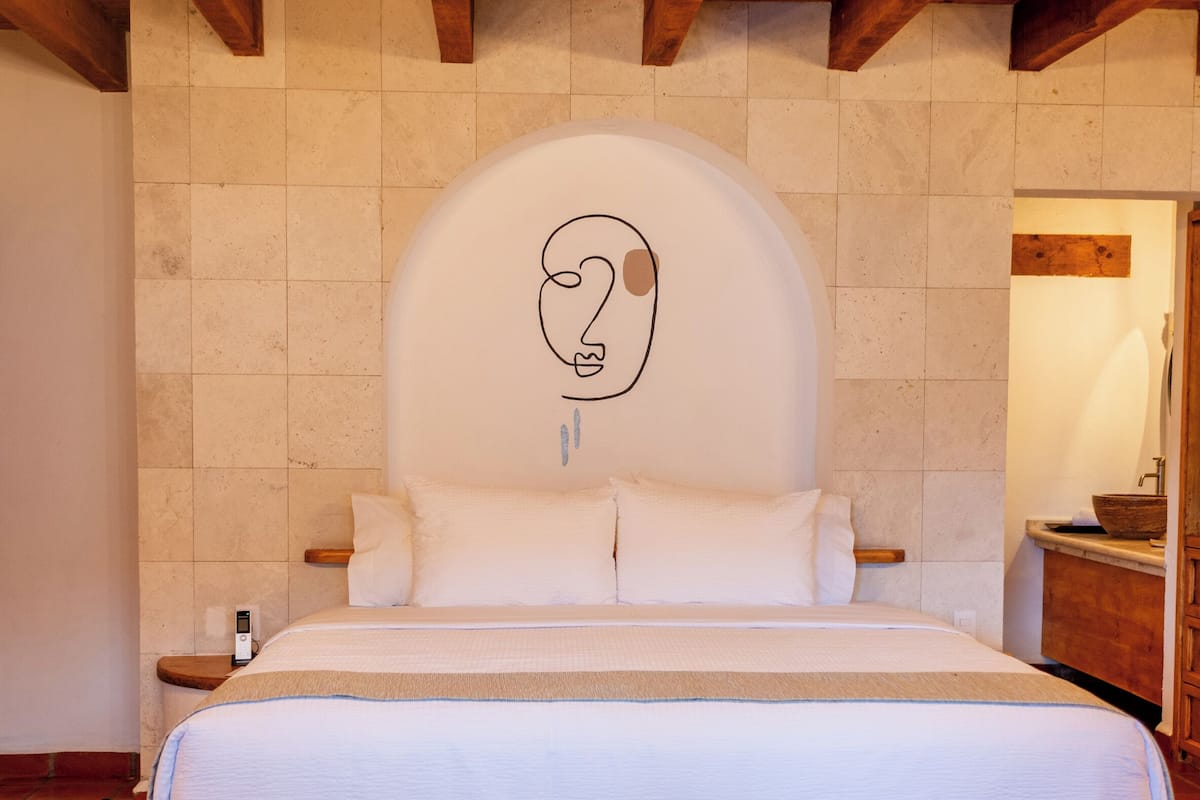 Un dormitorio con una cama grande, vigas de madera en el techo y suelo de baldosas.