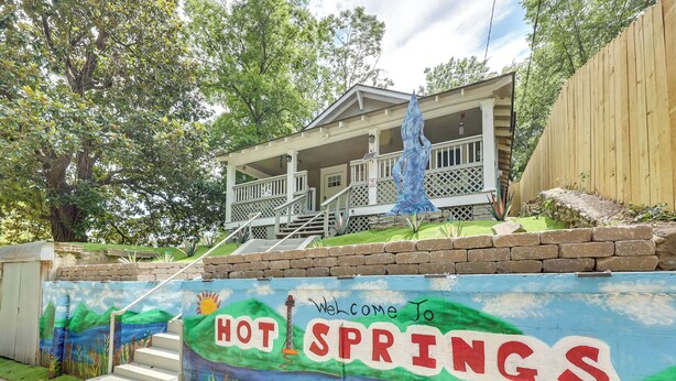 Et mural der byder besøgende velkommen til Hot Springs, med en trappe og en bygning med en veranda.