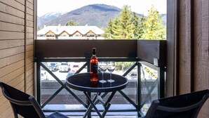 A balcony with a table and chairs, a bottle, and two glasses.