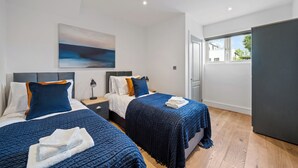 Een moderne hotelkamer met twee bedden, een groot raam en een schilderij aan de muur.
