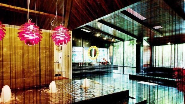 Un intérieur moderne agrémenté d’un élément décoratif aquatique réfléchissant, d’un plafond en bois et d’une décoration murale circulaire.