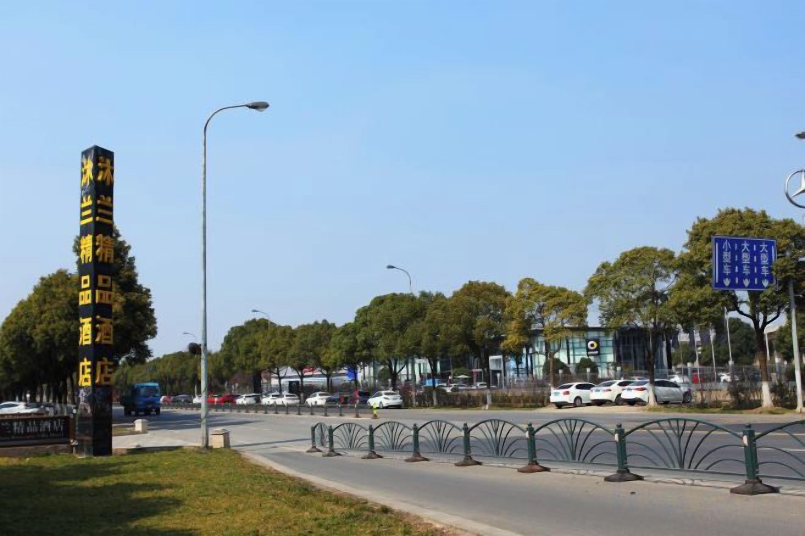 A street view with a tall signpost, a clear sky, and a road with vehicles.