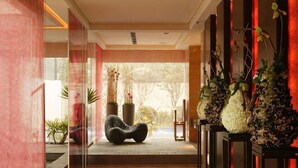 Un hall d’hôtel moderne, doté d’un espace salon, de plantes en pot et offrant une vue sur l’extérieur.