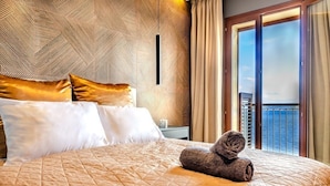 Ein Hotelzimmer mit einem großen Bett, Meerblick und einer Wand mit geometrischem Muster.