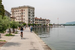 Eine Uferpromenade mit einem Radfahrer, Fußgängern und einer Reihe von Gebäuden am Wasser.