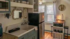 A kitchen with a stainless steel refrigerator, a sink with a towel, a microwave, and a shelf with mugs. - Chic 1-bedroom apartment with WiFi, AC in fabulous Sheboygan (Sheboygan)