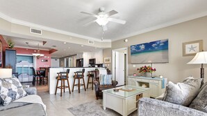 A spacious living room with a sofa, a coffee table, and a dining area with chairs. - Treasure Island 2210 (Panama City Beach)