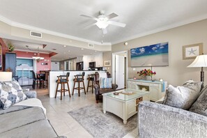 A spacious living room with a sofa, a coffee table, and a dining area with chairs. - Treasure Island 2210 (Panama City Beach)