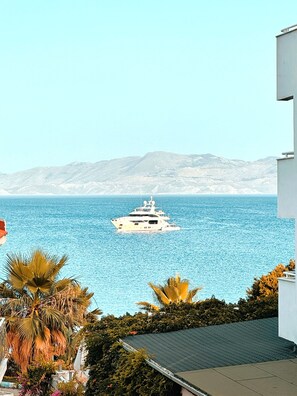 A large yacht on calm blue waters, with a mountainous backdrop and lush greenery in the foreground. - Tas Apart (Datça)