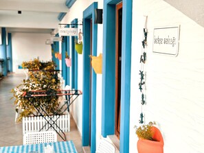 A corridor with blue doors, a checkered table, and potted plants. - Tas Apart (Datça)