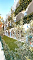 Un hotel con varios niveles de balcones, abundante vegetación y un jardín bien cuidado.