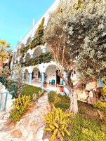 Un edificio con varios arcos y un jardín con plantas y un sendero.