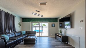 Una sala de estar moderna con un sofá modular, un televisor de pantalla plana y un ventanal corredero que da a un espacio al aire libre.