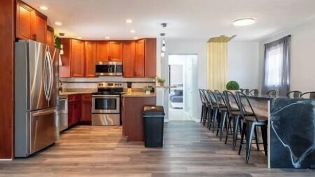 Una cocina moderna con armarios de madera, electrodomésticos de acero inoxidable y una isla central con taburetes de bar.