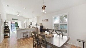 A spacious kitchen with a central island, wooden chairs, and a dining table.