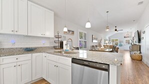 A modern kitchen with white cabinetry, granite countertops, and a dishwasher.