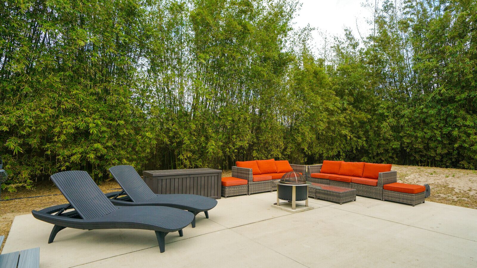 Un espace extérieur aménagé avec des fauteuils confortables, un canapé et un foyer.