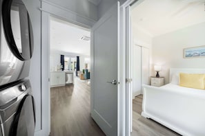 A hotel room with a bed, a nightstand, a lamp, and a view of the sea through the window.
