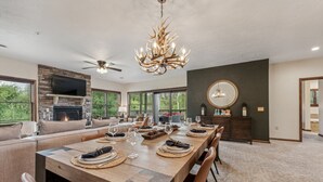 Un salón espacioso con chimenea, una amplia mesa de comedor preparada para seis personas y una moderna lámpara de araña.