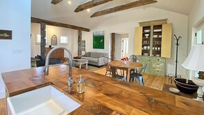 Una cocina moderna con encimera de madera, un lavamanos y una zona de comedor con mesa y sillas.