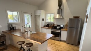 Una cocina moderna con una isla de madera, electrodomésticos de acero inoxidable y un ventanal grande.